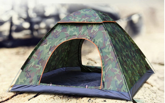 Camouflage-patterned tent set up on a sandy surface with blurred background
