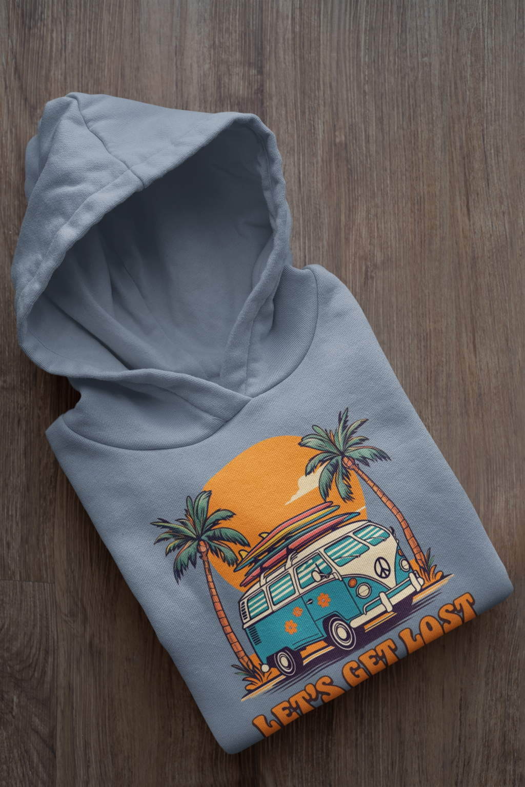 Folded hoodie with a van and palm tree design on a wooden surface