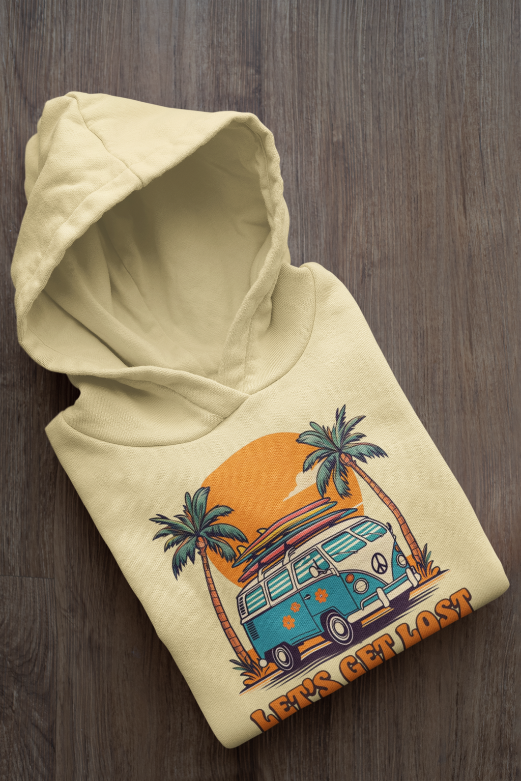 Beige hoodie with a graphic of a van and palm trees on a wooden surface