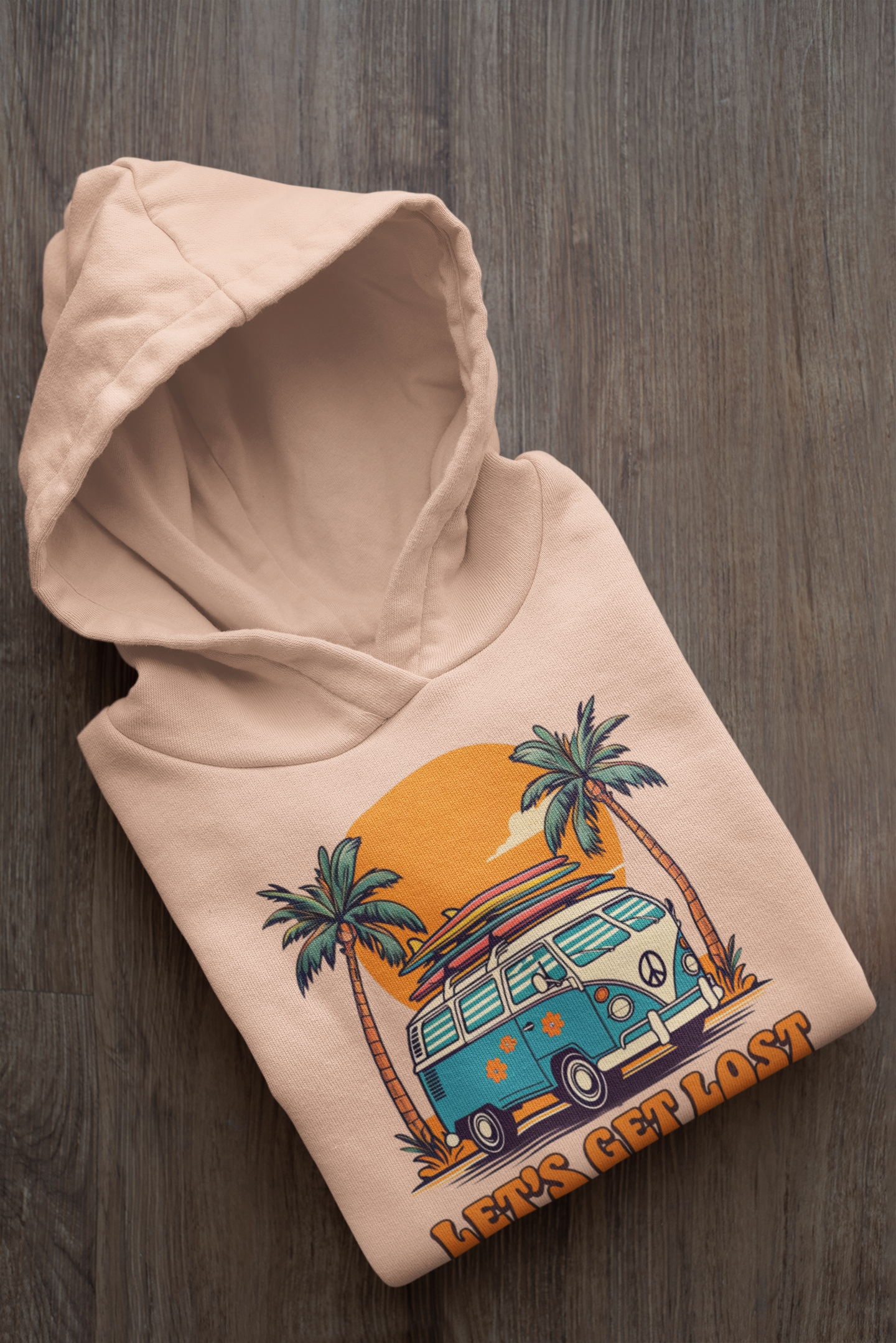 Beige hoodie with a graphic design of a van and palm trees on a wooden surface