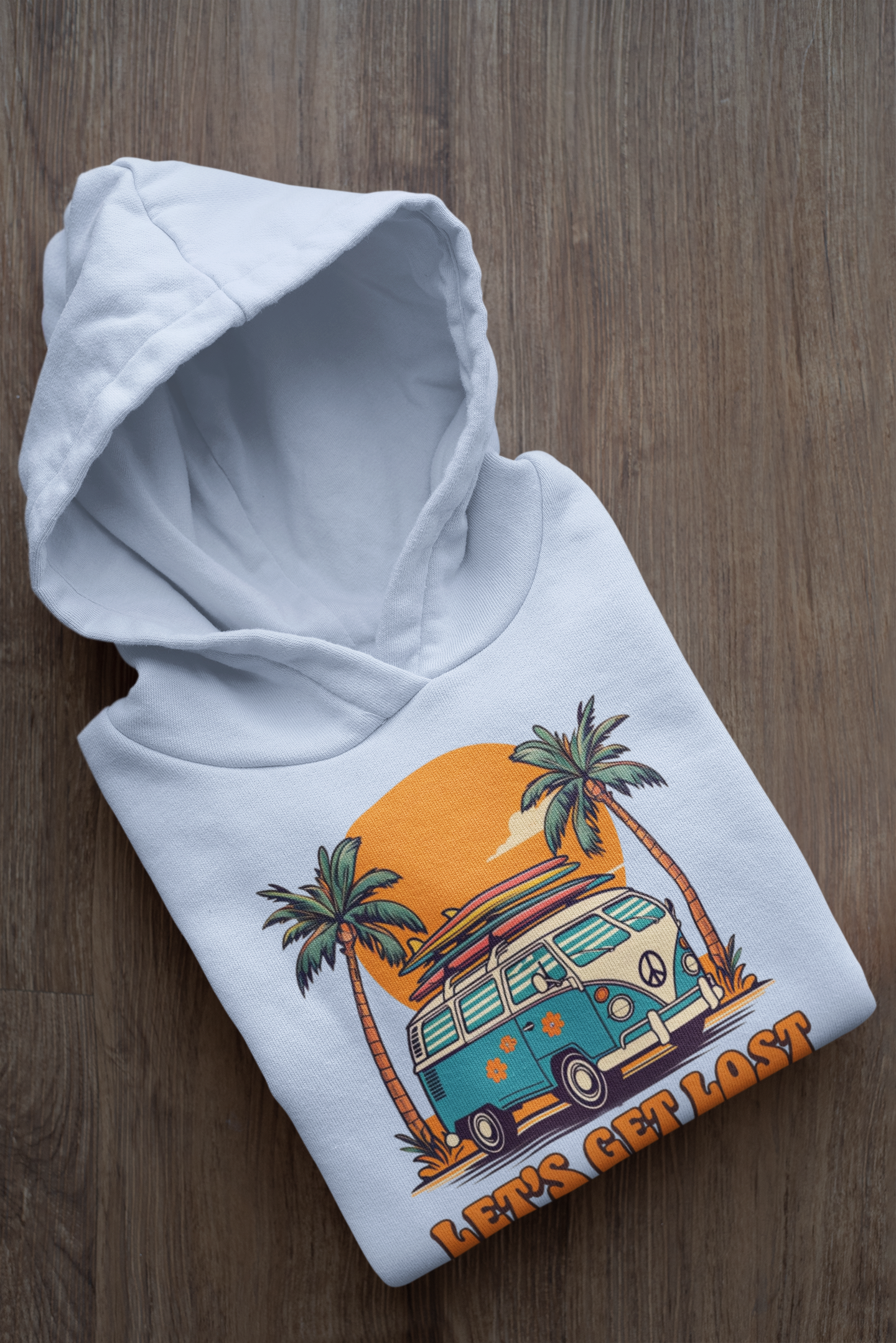 White hoodie with a colorful graphic of a van and palm trees on a wooden surface
