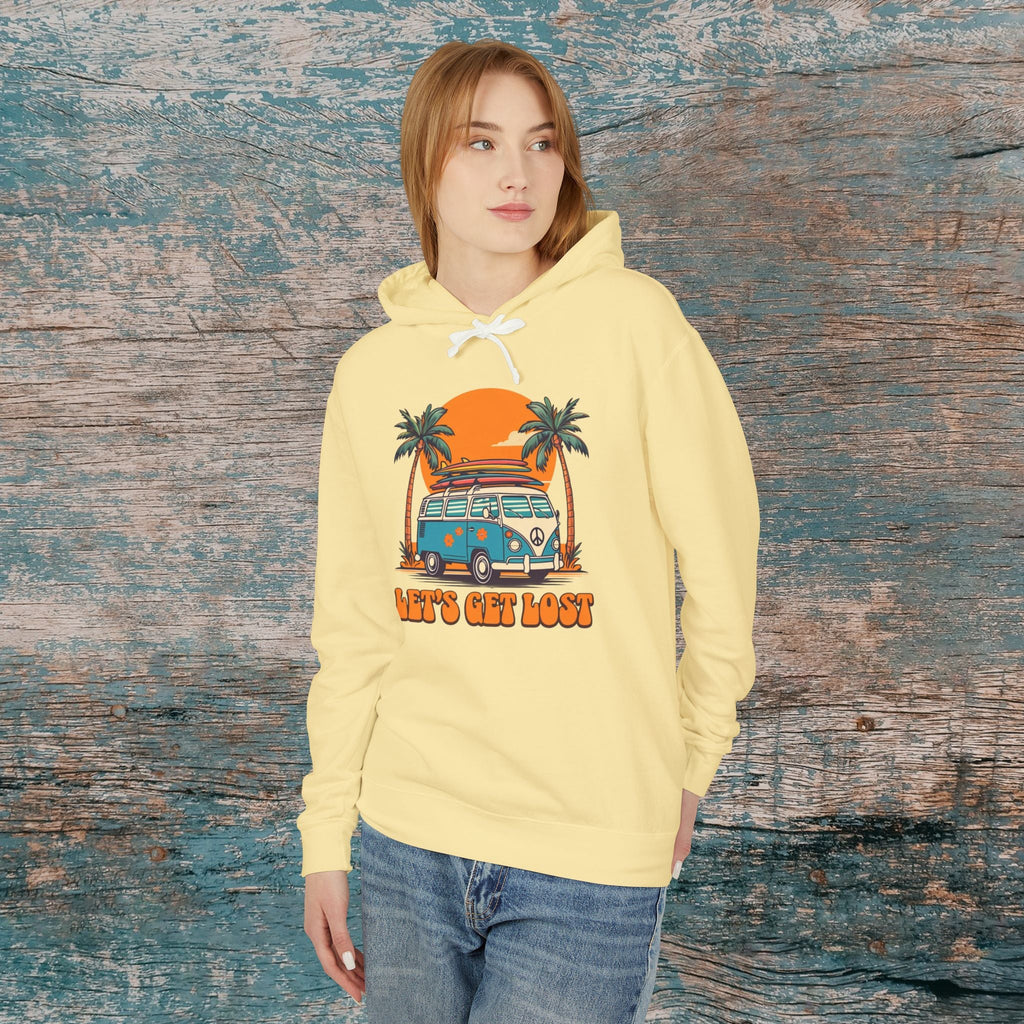 Person wearing a yellow hoodie with a graphic design of a van and palm trees, standing against a wooden background.