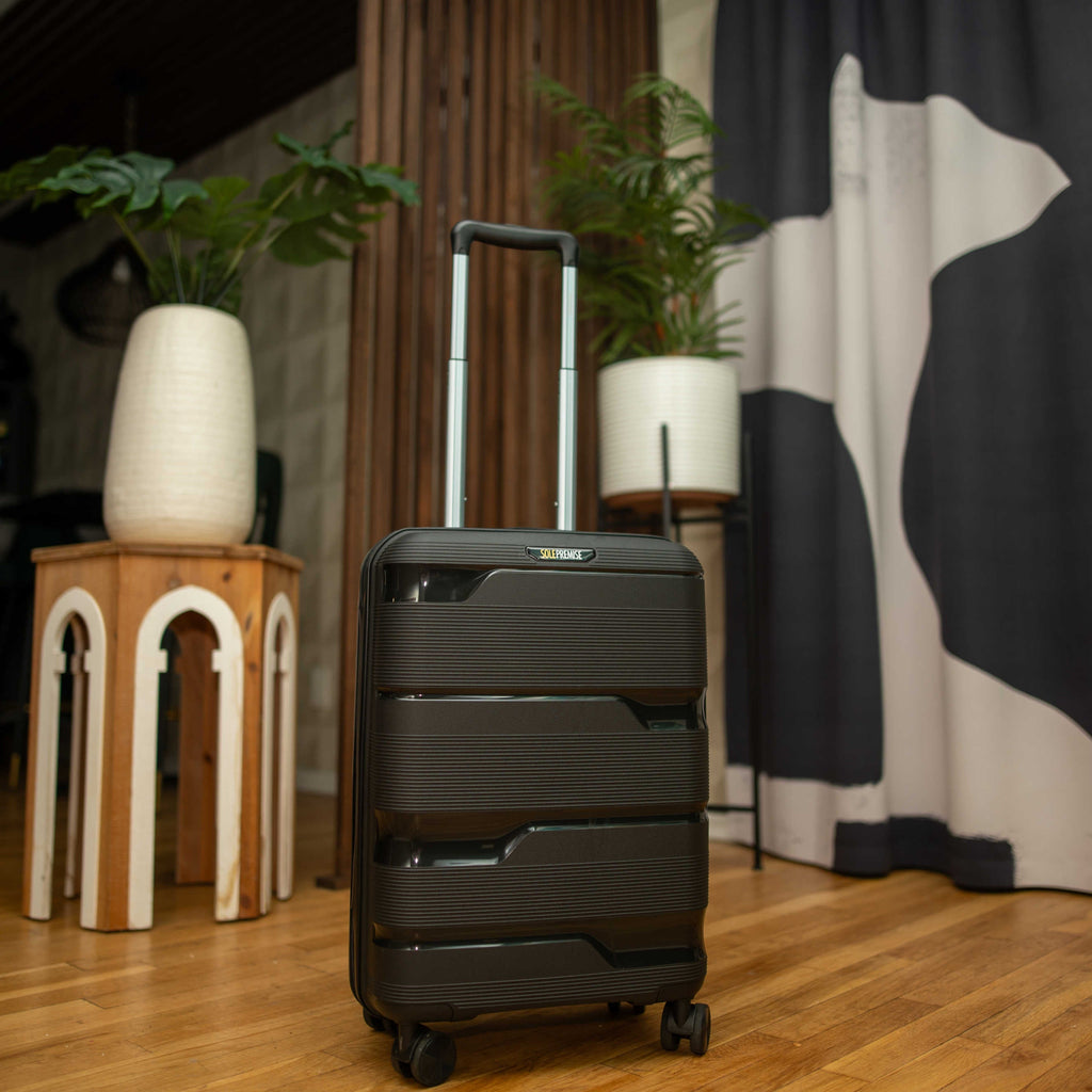 Black suitcase on a wooden floor with decorative plants and furniture in the background