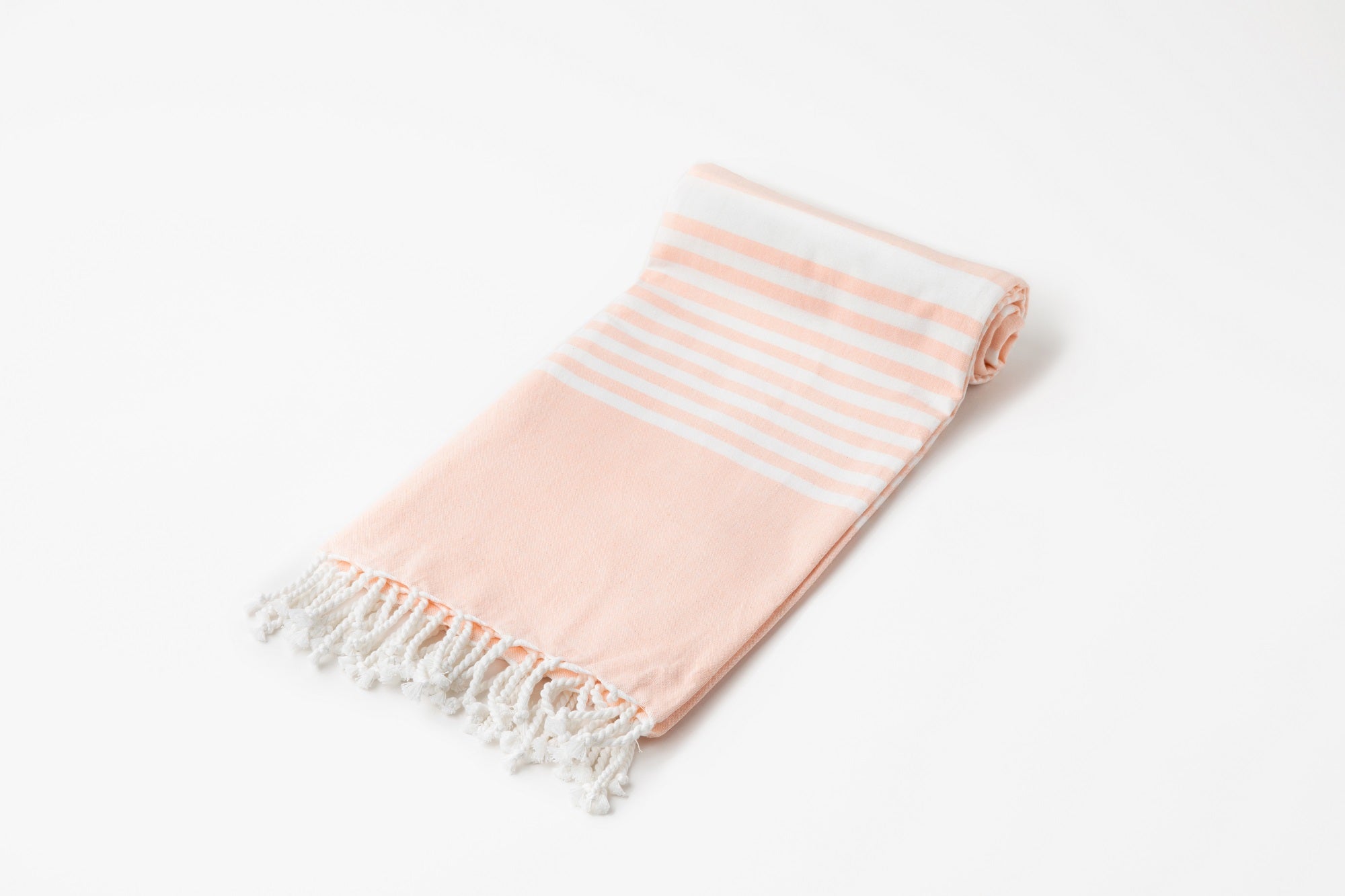 Pink and white striped towel with fringes on a light gray background