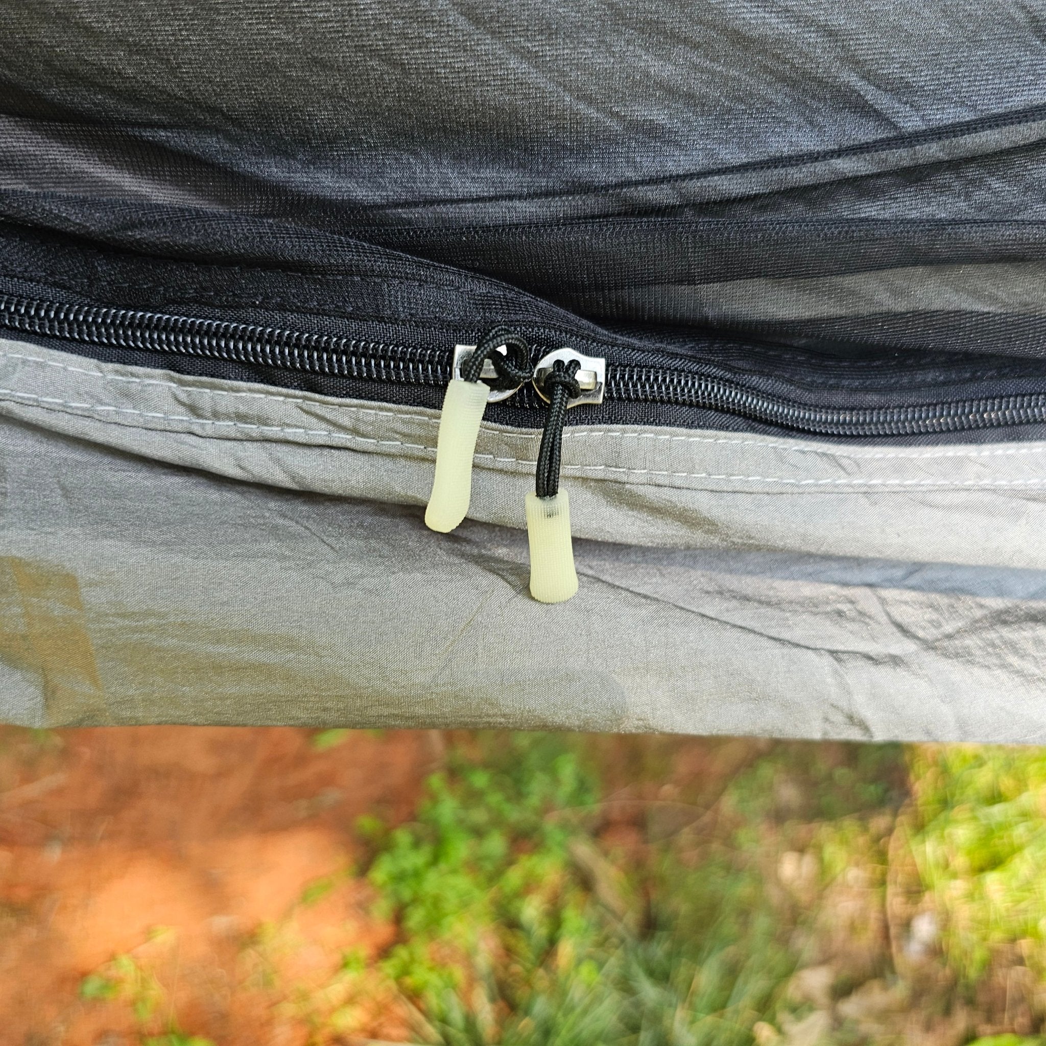 Close-up of a zipper on a fabric surface with a blurred natural background