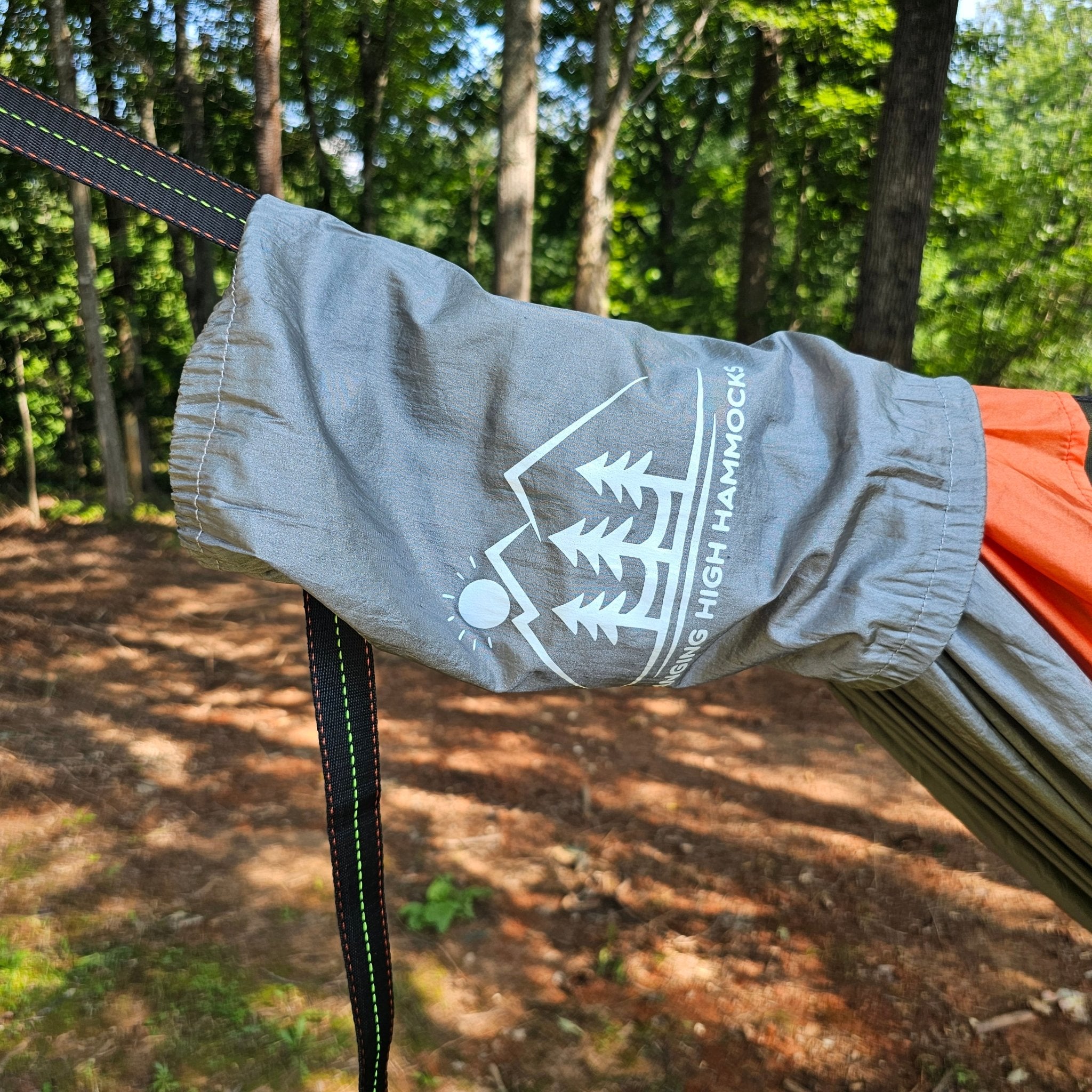 Gray hammock with a logo hanging in a forest setting