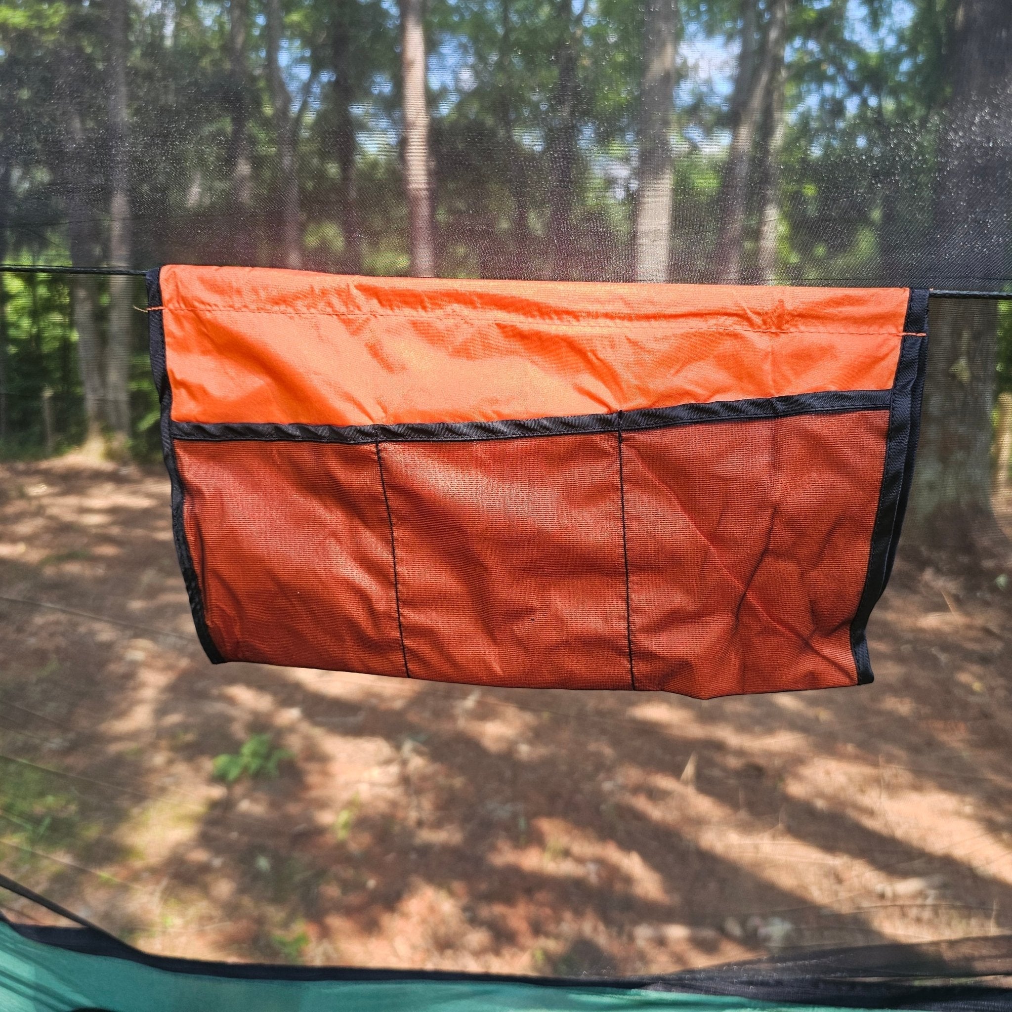 Orange hammock accessory hanging on a hammock with a forest background