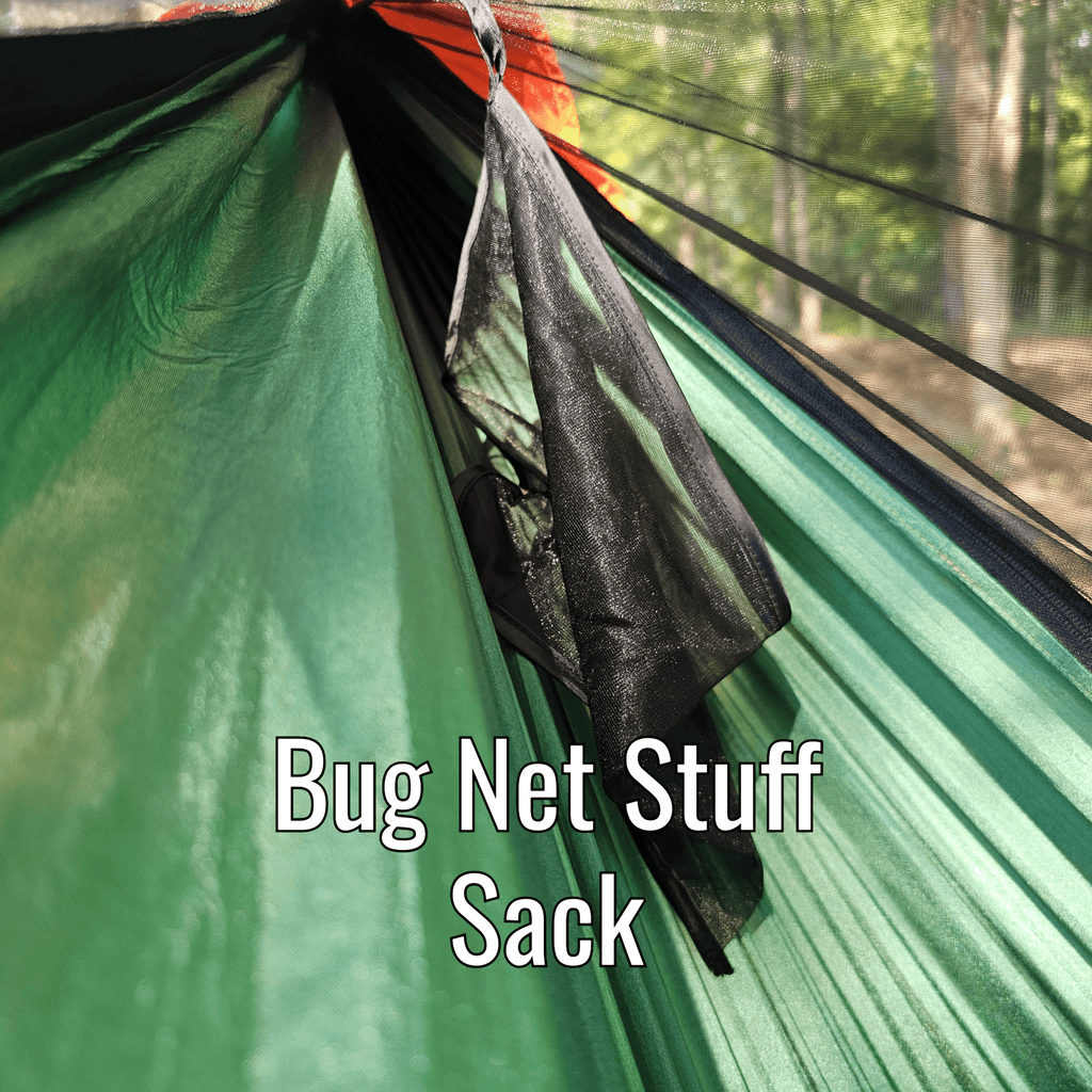 Green hammock with a black bug net stuff sack in a forest setting