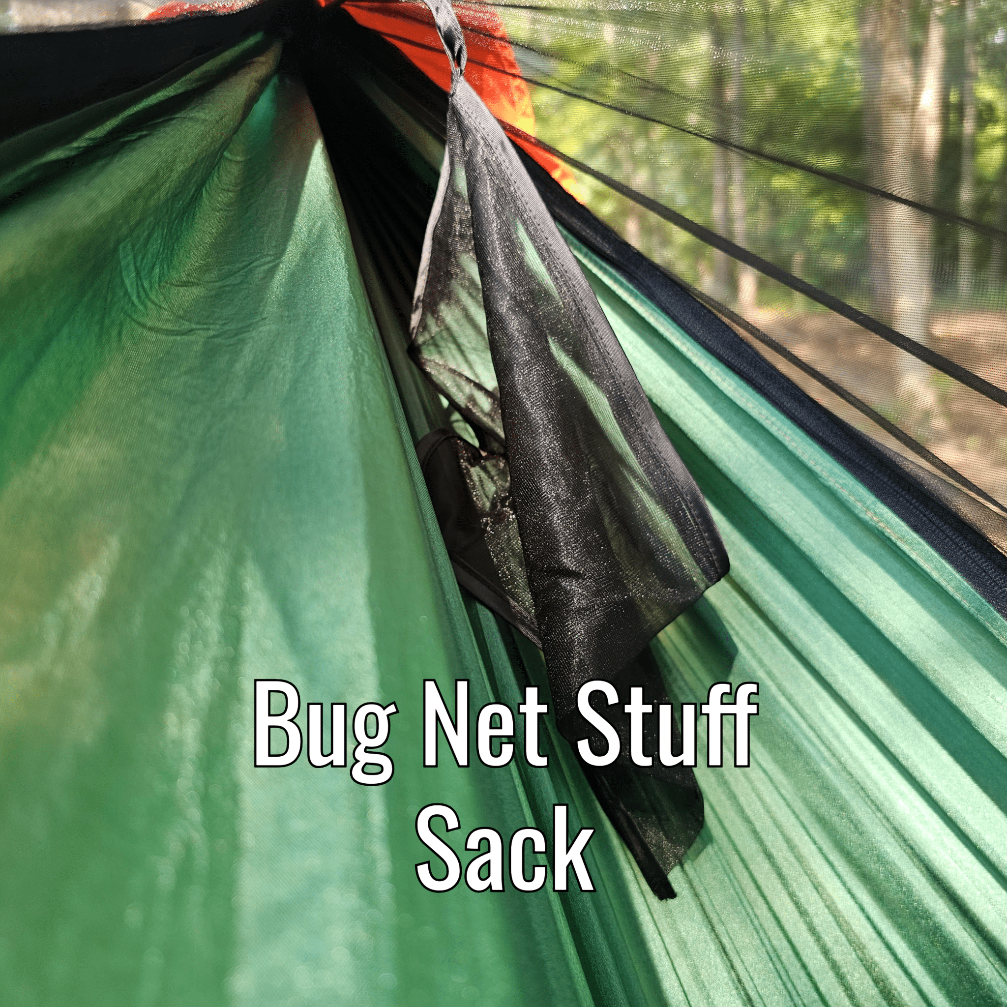 Green hammock with a black bug net stuff sack in a forest setting