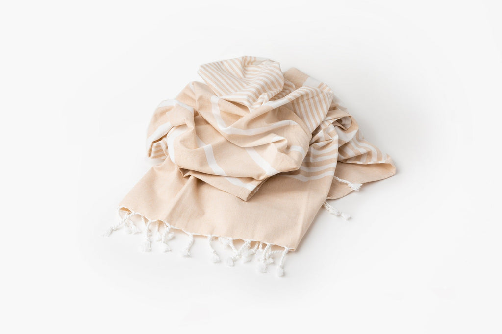 Beige towel with white stripes and tassels on a white background